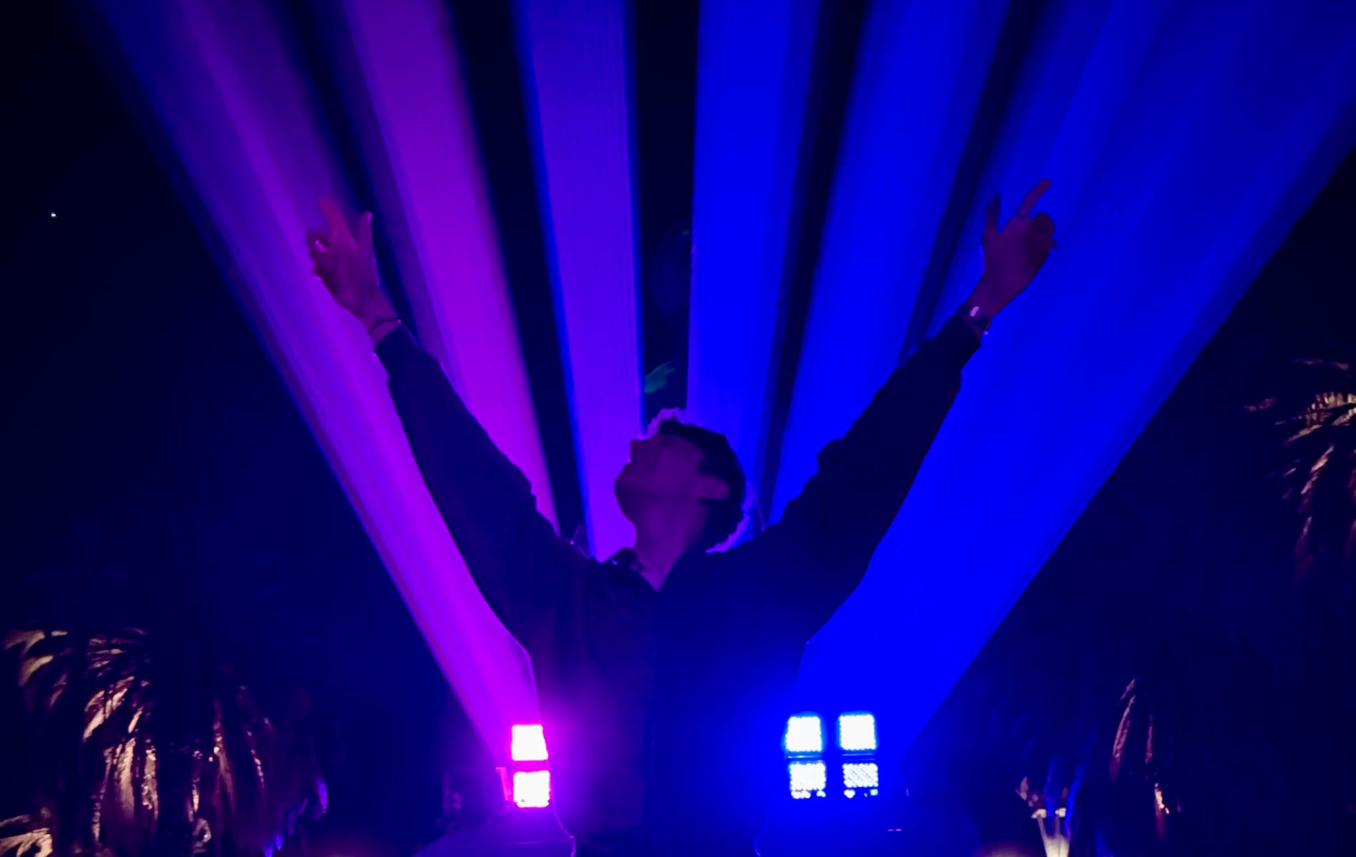 Arms raised underneath the purple laser beams