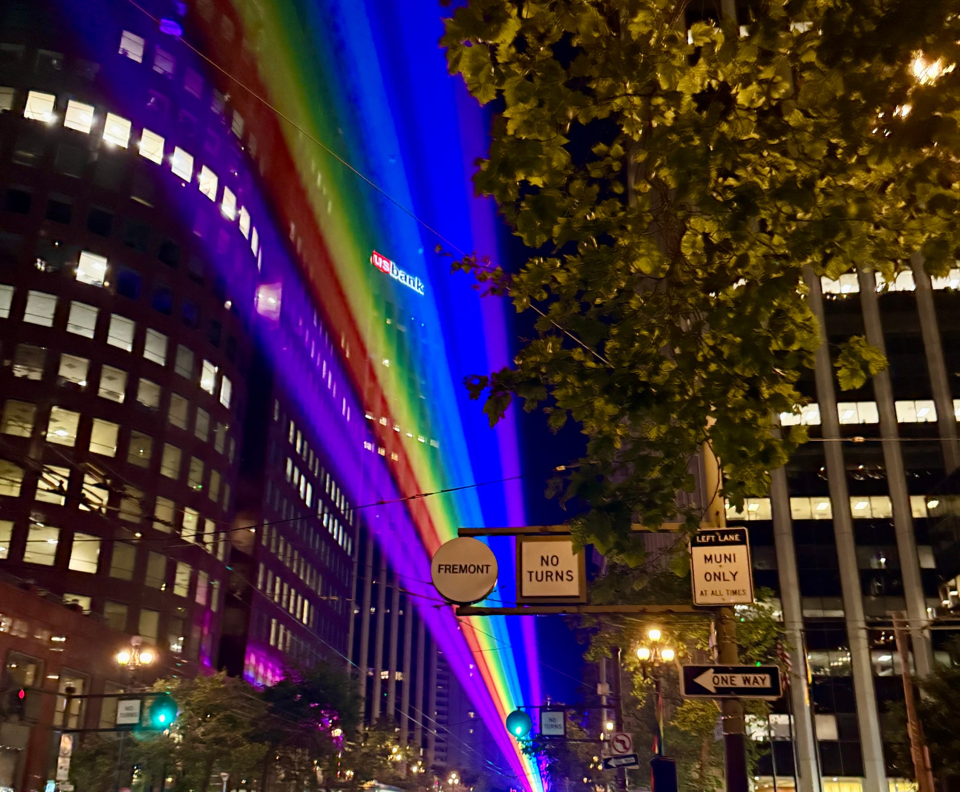 Rainbow lasers stretching down Market Street at night